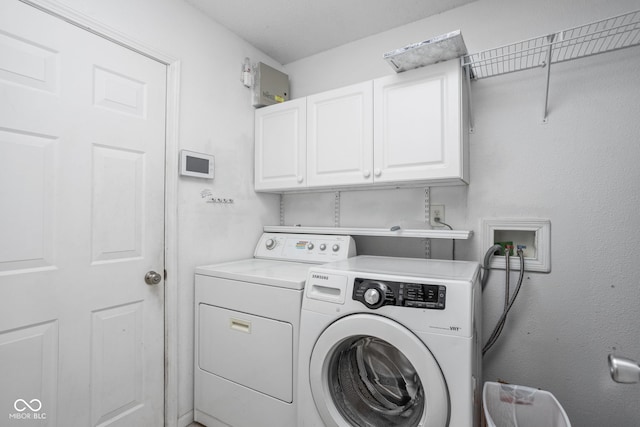 laundry area with washing machine and dryer and cabinets