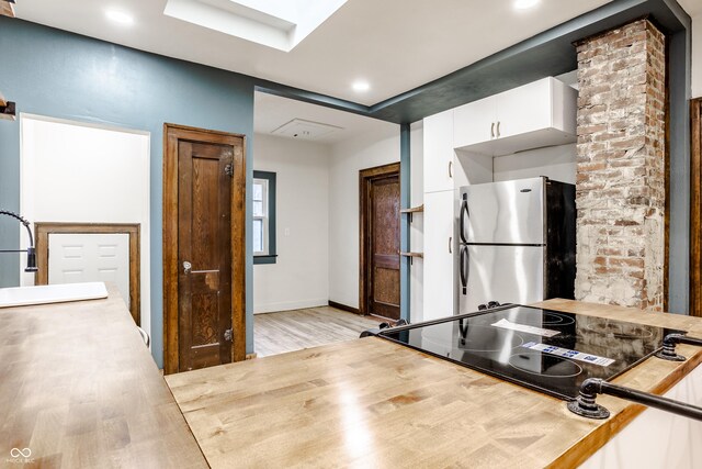 kitchen with white cabinetry, stainless steel fridge, sink, and light wood-type flooring