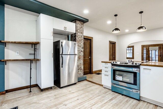 kitchen featuring white cabinets, appliances with stainless steel finishes, decorative light fixtures, and light hardwood / wood-style flooring