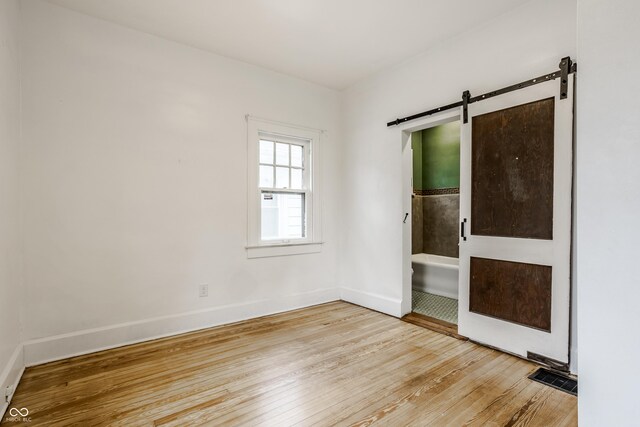 spare room with light wood-type flooring and a barn door