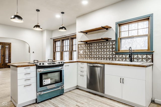 kitchen featuring pendant lighting, sink, light hardwood / wood-style flooring, white cabinetry, and stainless steel appliances