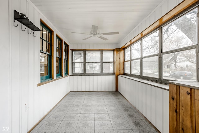 unfurnished sunroom featuring ceiling fan and a healthy amount of sunlight