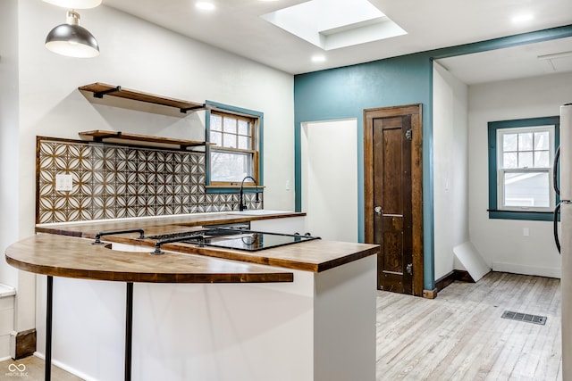 kitchen featuring wooden counters, light hardwood / wood-style floors, tasteful backsplash, and a wealth of natural light