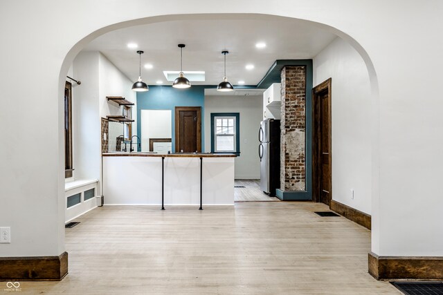 kitchen featuring stainless steel fridge, light hardwood / wood-style flooring, pendant lighting, and sink