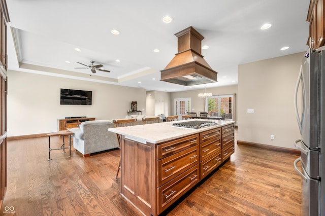 kitchen featuring a kitchen breakfast bar, stainless steel appliances, a tray ceiling, hardwood / wood-style flooring, and a kitchen island