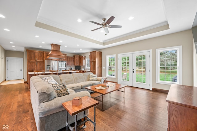 living room featuring french doors, a raised ceiling, ceiling fan, dark wood-type flooring, and crown molding