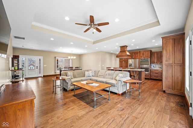 living room featuring light hardwood / wood-style flooring, a raised ceiling, and crown molding