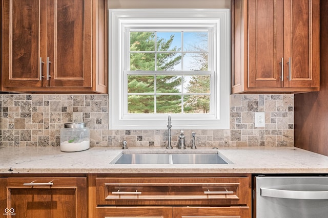 kitchen with stainless steel dishwasher, backsplash, light stone counters, and sink