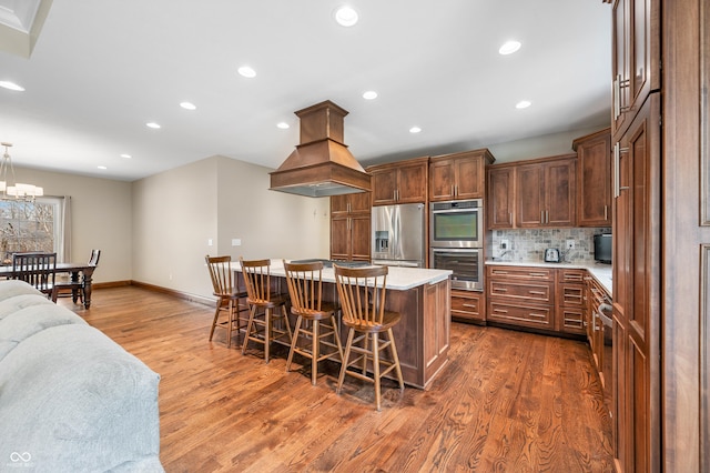 kitchen with a center island, a kitchen bar, hanging light fixtures, dark hardwood / wood-style flooring, and stainless steel appliances