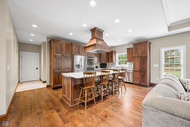 kitchen featuring dark wood-type flooring, a kitchen breakfast bar, decorative backsplash, a kitchen island, and appliances with stainless steel finishes