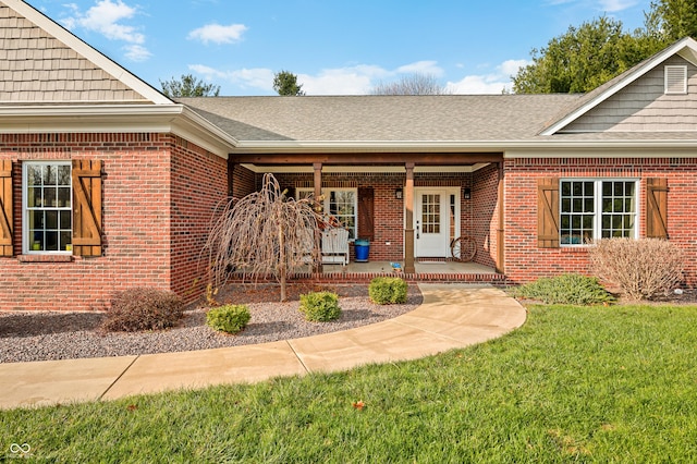 doorway to property featuring a lawn and covered porch