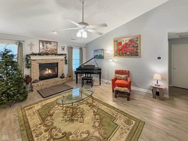 living area with ceiling fan, light hardwood / wood-style flooring, lofted ceiling, and a brick fireplace