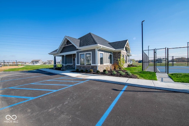 5607 Tart Blvd, Indianapolis, IN 46239 - view of front facade with stone siding, uncovered parking, a shingled roof, and a gate