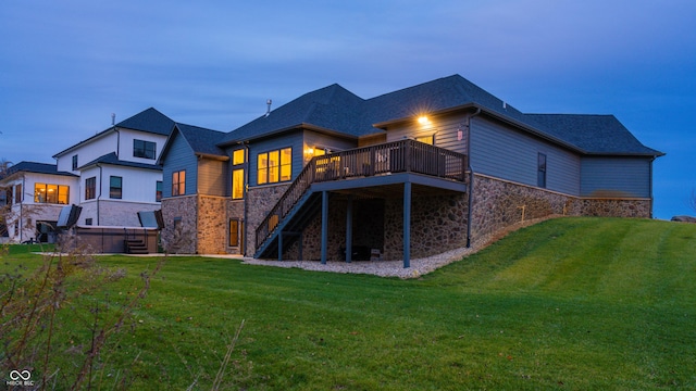 back house at dusk featuring a lawn and a wooden deck