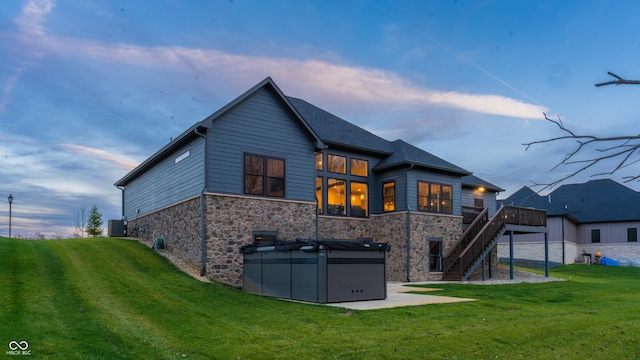 back house at dusk with a yard, cooling unit, and a deck