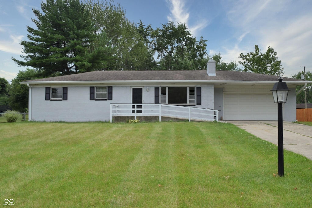 single story home featuring a garage and a front lawn