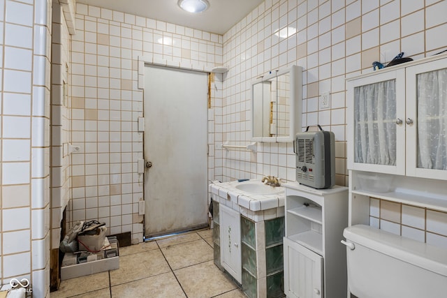 bathroom featuring tile patterned floors, sink, tile walls, and toilet