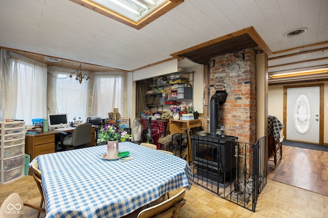 dining room featuring a notable chandelier, a wood stove, and light parquet floors