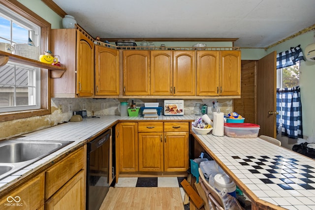 kitchen with backsplash, tile counters, a healthy amount of sunlight, and black dishwasher