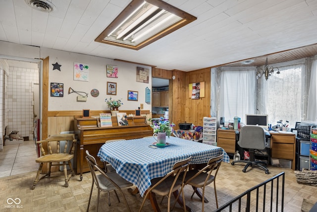 dining room featuring wooden walls, light parquet flooring, and a notable chandelier