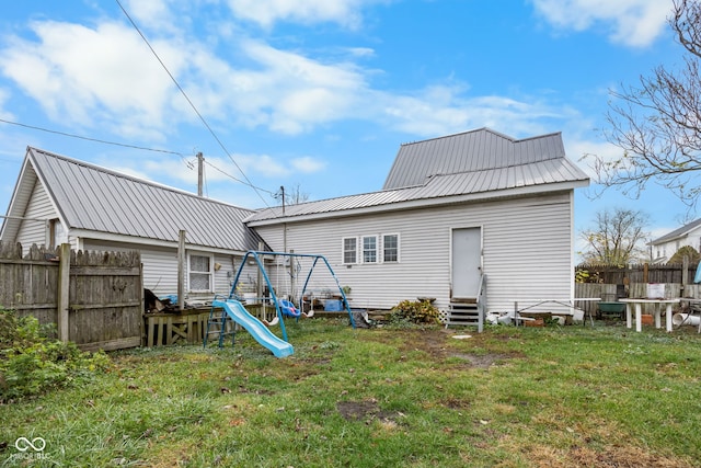 back of property with a playground and a yard