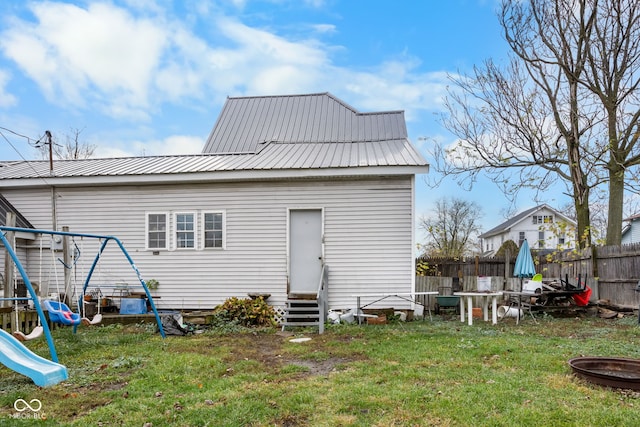 rear view of house featuring a lawn and a playground