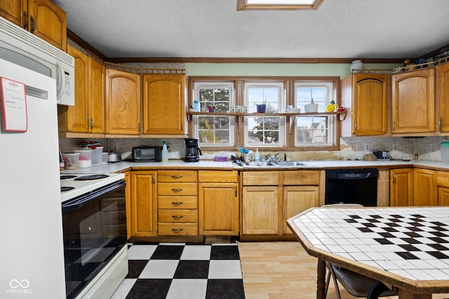 kitchen with backsplash, white appliances, crown molding, sink, and tile counters