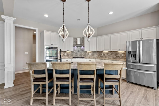10346 Strongbow Rd, Fishers, IN 46040 - kitchen featuring appliances with stainless steel finishes, wall chimney range hood, decorative columns, backsplash, and white cabinetry