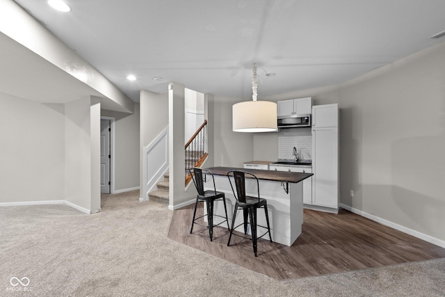10346 Strongbow Rd, Fishers, IN 46040 - kitchen featuring stainless steel microwave, a breakfast bar, light colored carpet, recessed lighting, and a kitchen island