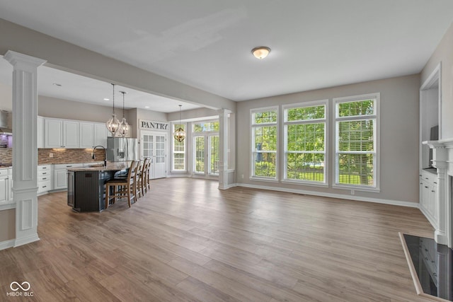 10346 Strongbow Rd, Fishers, IN 46040 - kitchen with stainless steel fridge, decorative columns, open floor plan, white cabinetry, and a kitchen bar