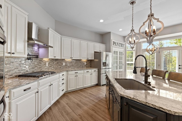10346 Strongbow Rd, Fishers, IN 46040 - kitchen with wall chimney exhaust hood, stainless steel appliances, white cabinets, a chandelier, and tasteful backsplash