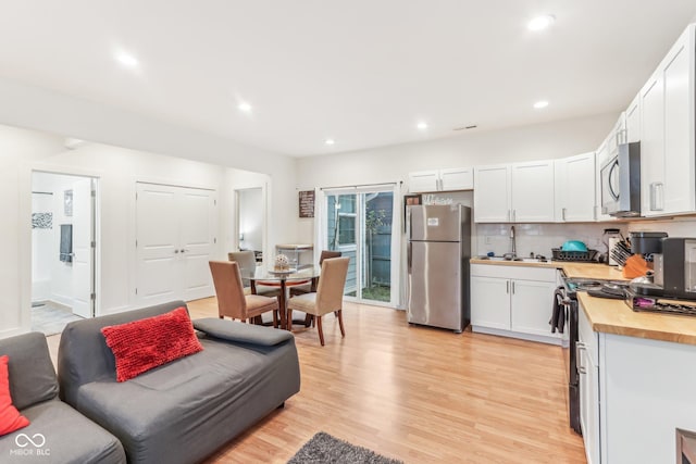 359 Terrace Ave, Indianapolis, IN 46225 - kitchen featuring white cabinets, light wood finished floors, decorative backsplash, butcher block countertops, and appliances with stainless steel finishes