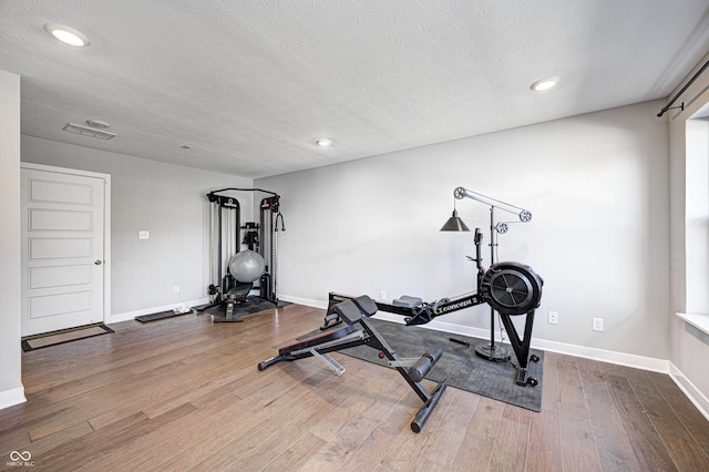 workout room with hardwood / wood-style floors and a textured ceiling