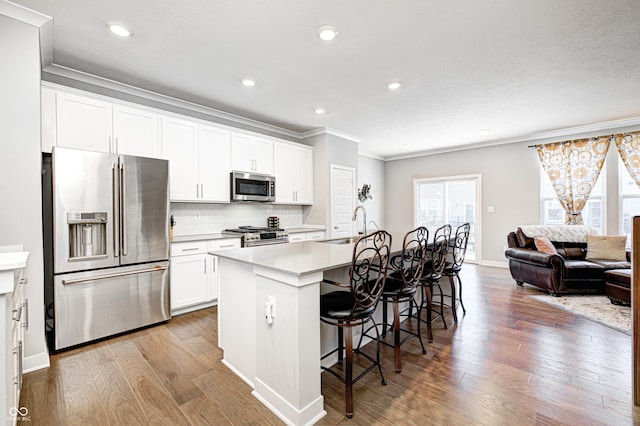 kitchen featuring a kitchen bar, appliances with stainless steel finishes, white cabinetry, and a kitchen island with sink