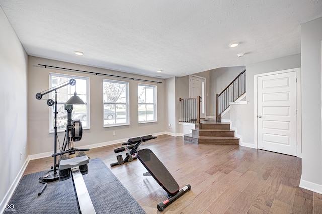 workout area featuring a healthy amount of sunlight, a textured ceiling, and light hardwood / wood-style flooring