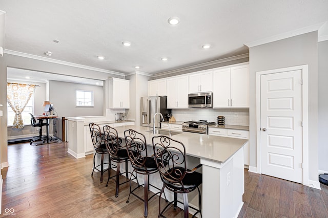 kitchen featuring white cabinetry, dark hardwood / wood-style floors, a breakfast bar area, a kitchen island with sink, and appliances with stainless steel finishes