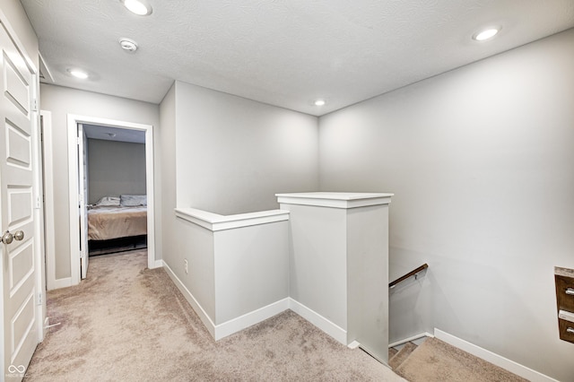 hallway featuring a textured ceiling and light colored carpet