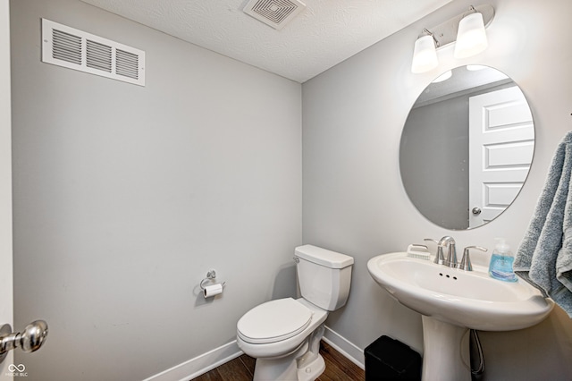 bathroom featuring a textured ceiling, hardwood / wood-style flooring, and toilet