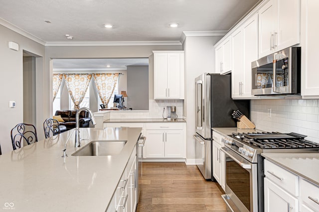 kitchen featuring white cabinets, appliances with stainless steel finishes, light hardwood / wood-style flooring, and sink