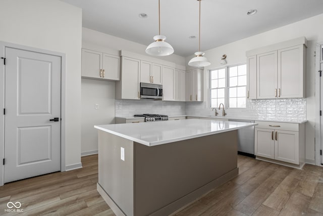 kitchen featuring white cabinetry, stainless steel appliances, decorative light fixtures, and a kitchen island