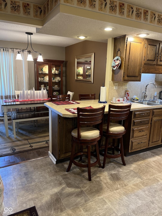 bar featuring pendant lighting, backsplash, a textured ceiling, and sink