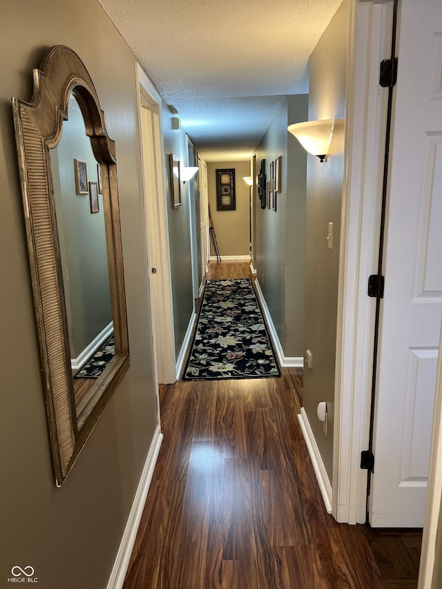 hallway with a textured ceiling and dark wood-type flooring