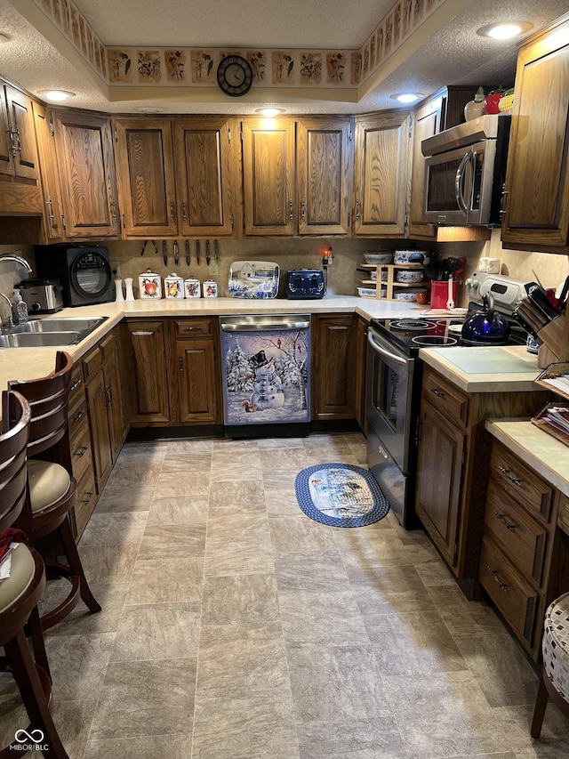 kitchen featuring a textured ceiling, stainless steel appliances, and sink