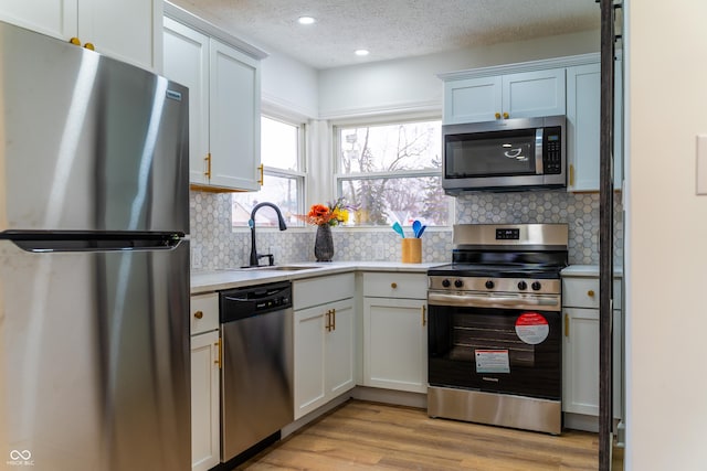 kitchen with sink, white cabinets, a textured ceiling, and appliances with stainless steel finishes