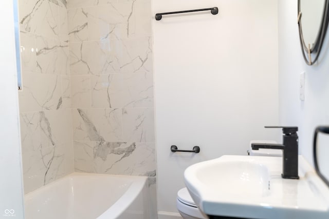 full bathroom featuring tiled shower / bath combo, toilet, and sink