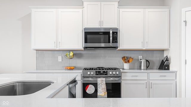 kitchen with white cabinets, light stone counters, and appliances with stainless steel finishes