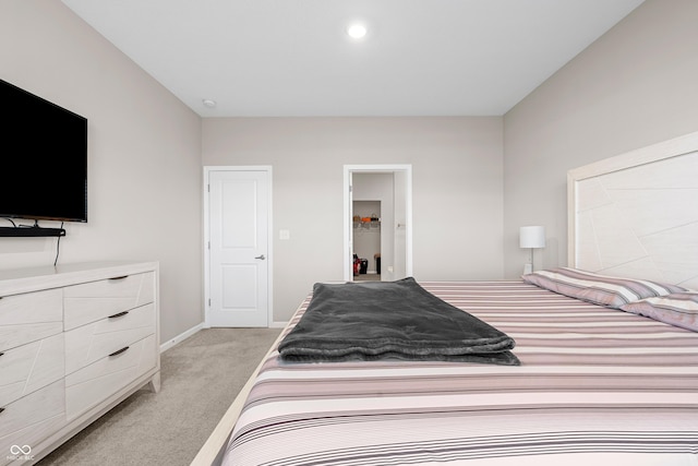 bedroom featuring a walk in closet, light carpet, and a closet