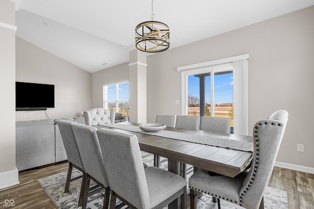 dining space featuring wood-type flooring, plenty of natural light, lofted ceiling, and a notable chandelier