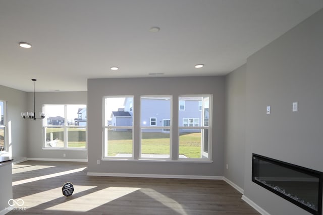 unfurnished living room featuring dark hardwood / wood-style floors, a wealth of natural light, and a chandelier