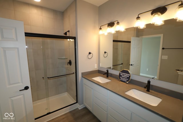 bathroom with hardwood / wood-style floors, vanity, and an enclosed shower